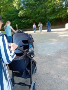 Image of a black pram with mums walking against a backdrop of green trees at a pregnancy walk in Roundhay Park Leeds.