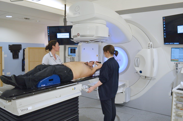 patient on treatment machine couch with two radiographers