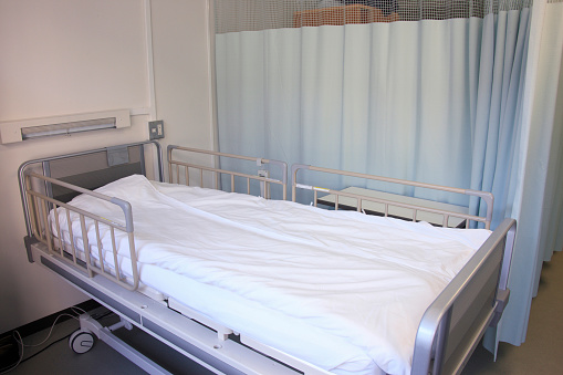 Hospital bed with metal side rails raised on both sides.