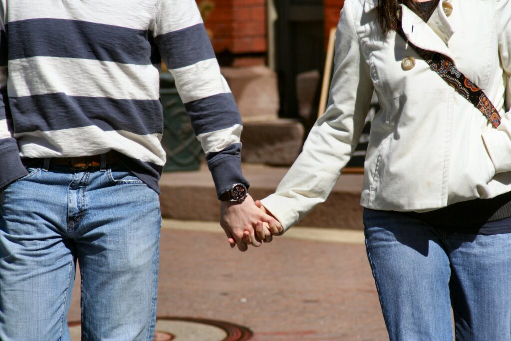 Two young adults walking along holding hands