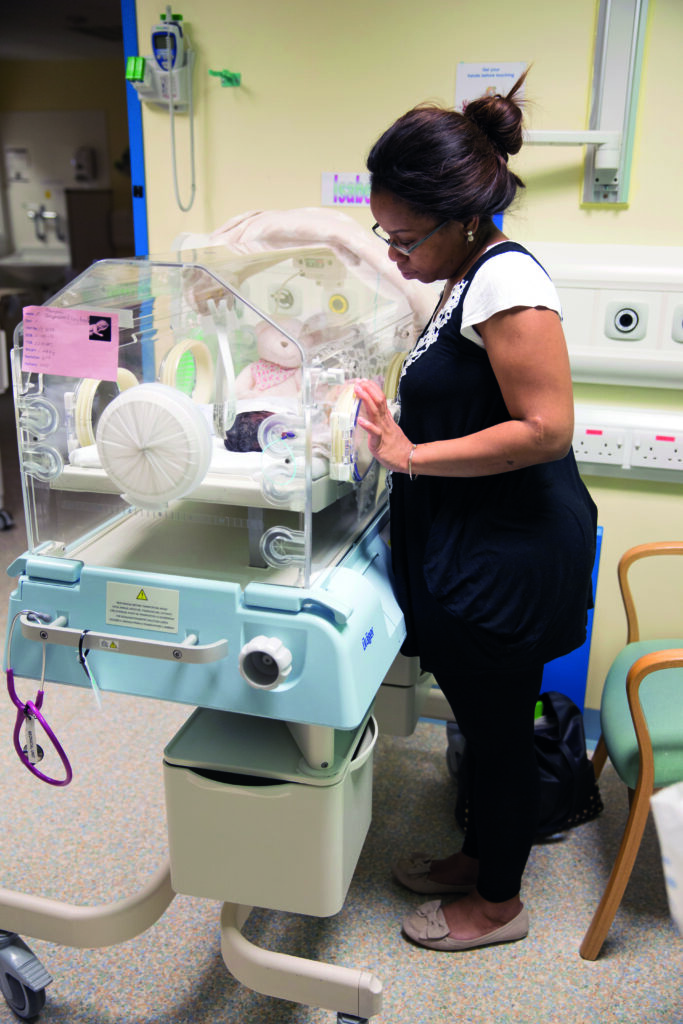 Photograph of a parent checking their baby's bubble. The floor space is clear.