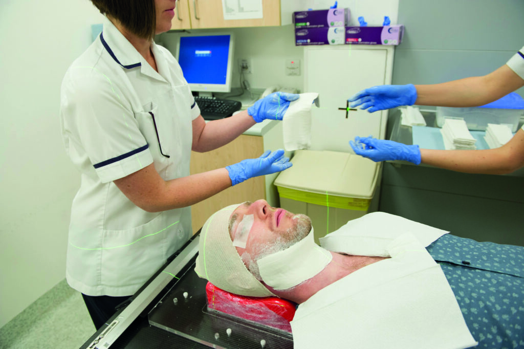 Photograph showing mould room staff placing plaster of Paris bandages on patient.