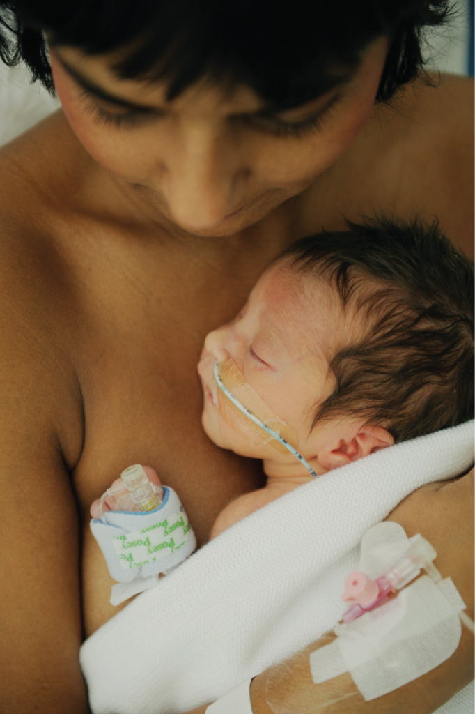Parent holding a baby with a feeding tube against their chest during skin-to-skin contact.