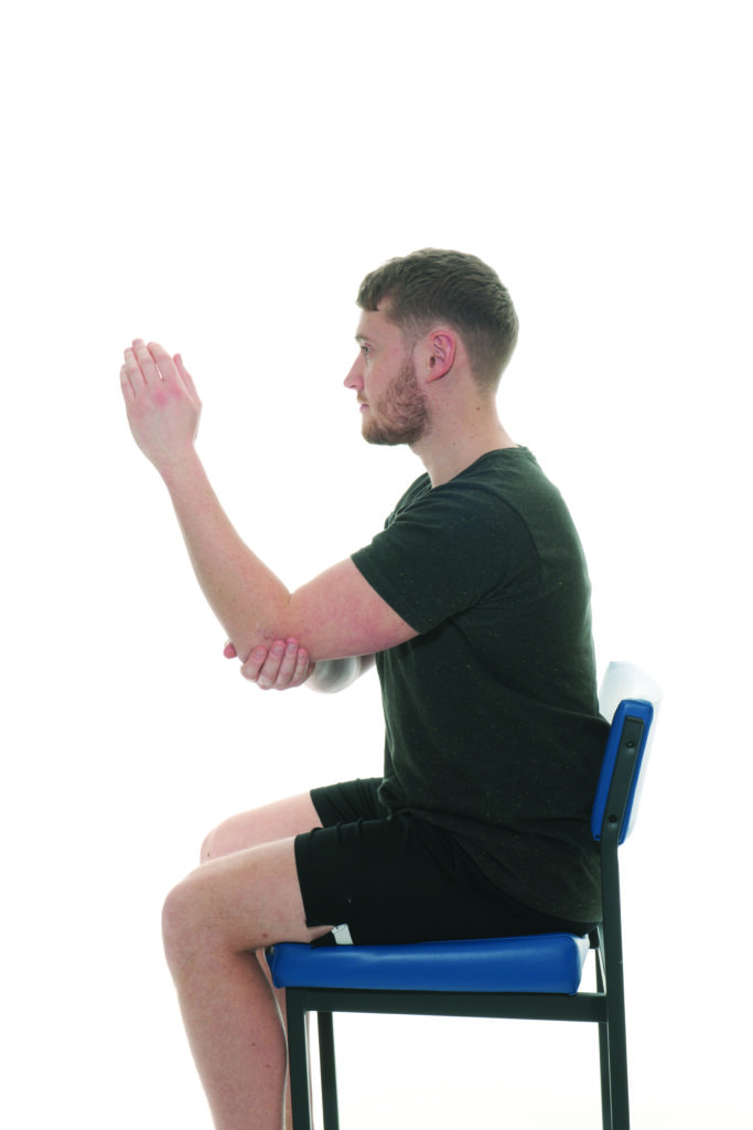 Photograph of a person sat in a chair with their arm relaxed in front of them