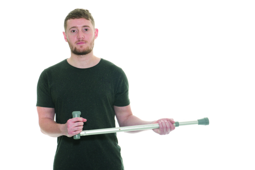 Photograph of a person holding a crutch in both hands pushed to the side