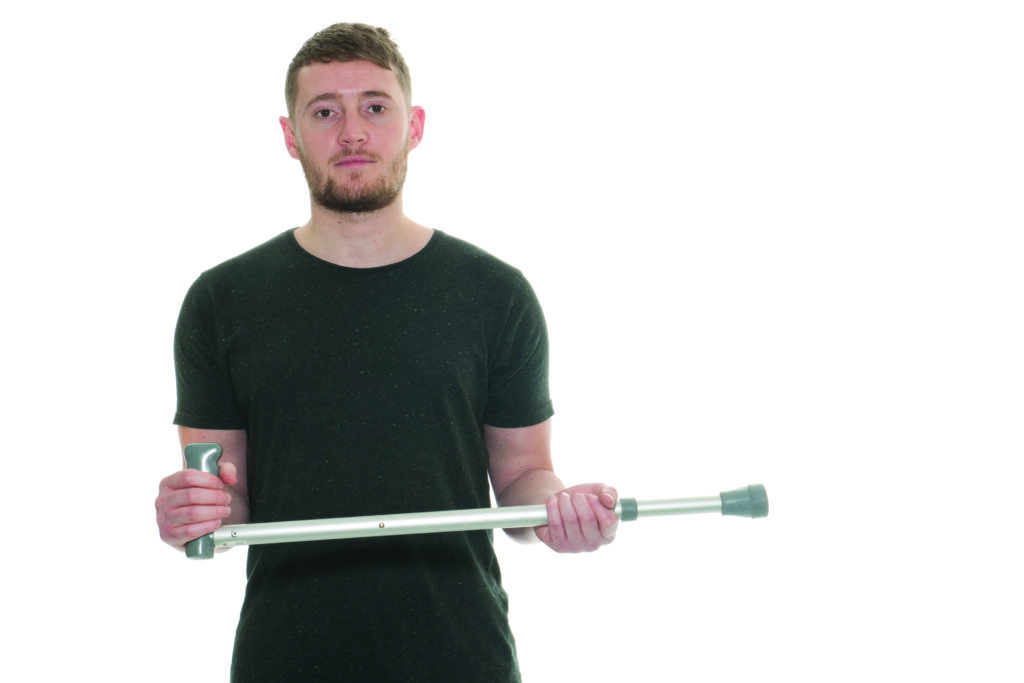 Photograph of a person holding a crutch in both hands in front of them