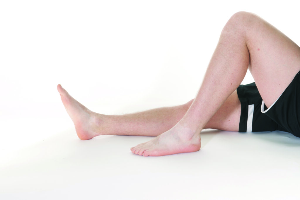 Photograph of a person with one leg laying flat and the other bent with knee raised