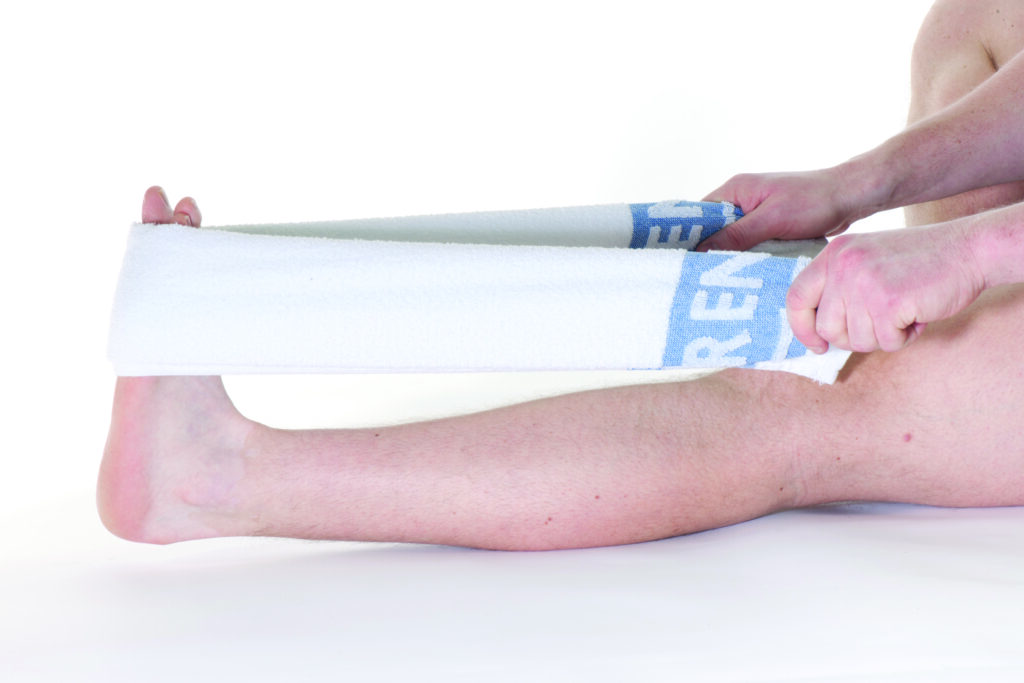 Photograph of a persons legs a towel wrapped around it and hands stretching the towel