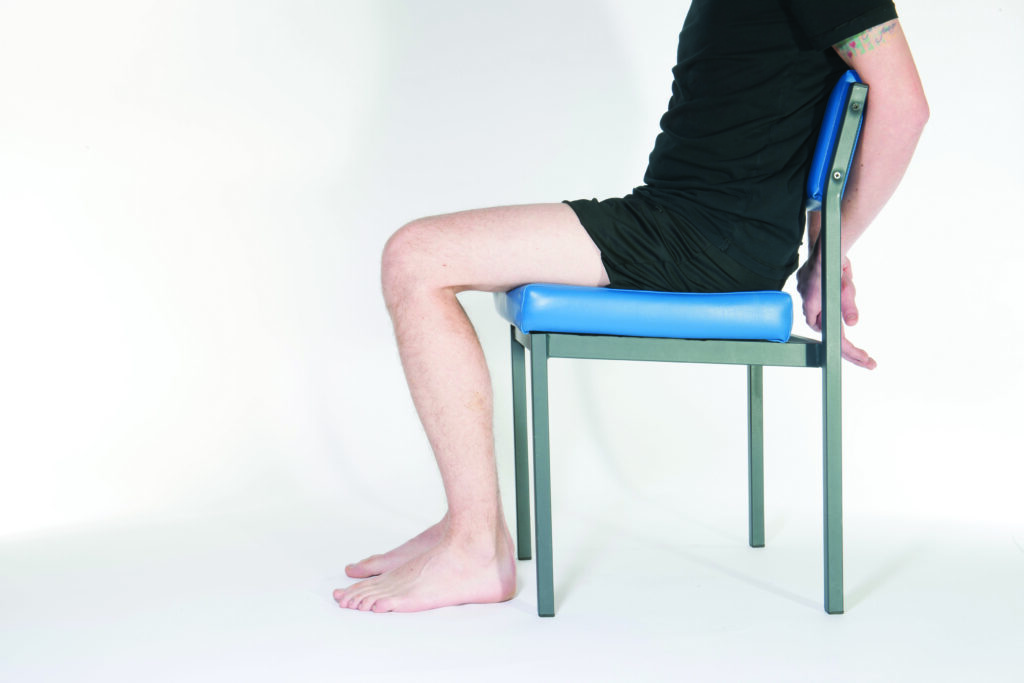 Photograph of a person sat on a chair with legs relaxed