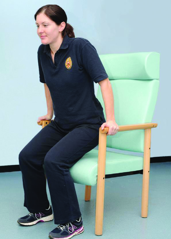 A photograph of a person lifting their bottom whilst sat in a chair.
