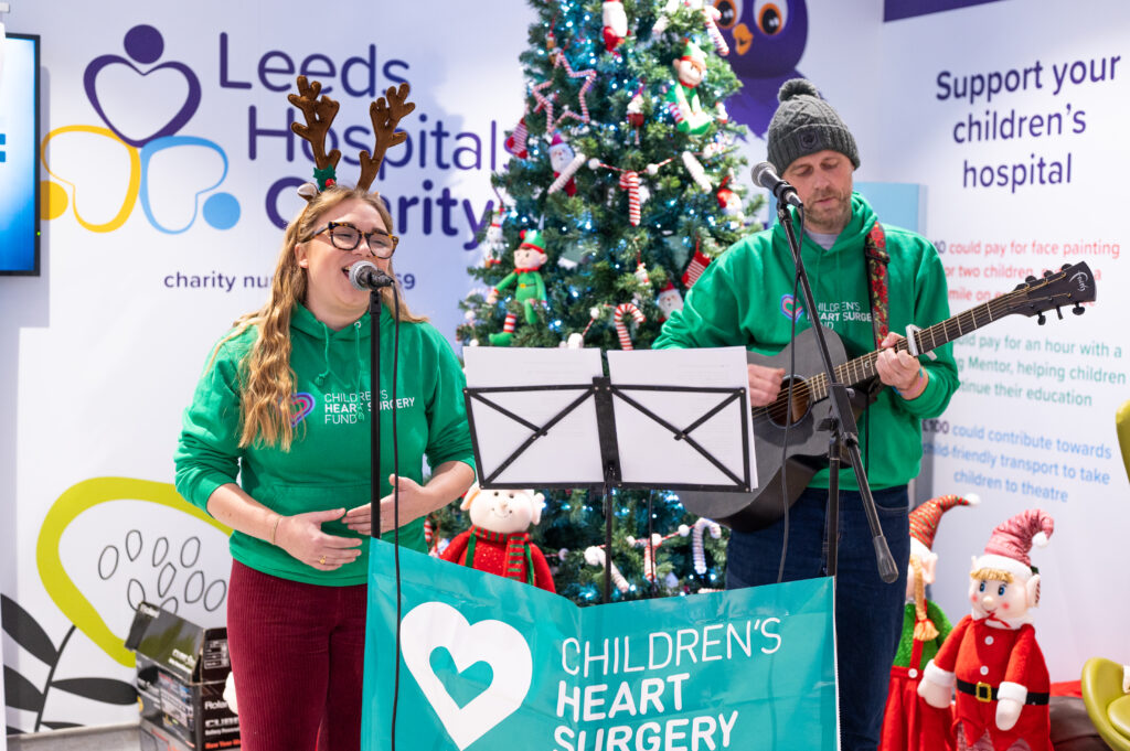 An image showing a band of two people singing and playing the guitar to Christmas Songs at the Leeds Children's Hospital Christmas Lights 2023 Switch on.