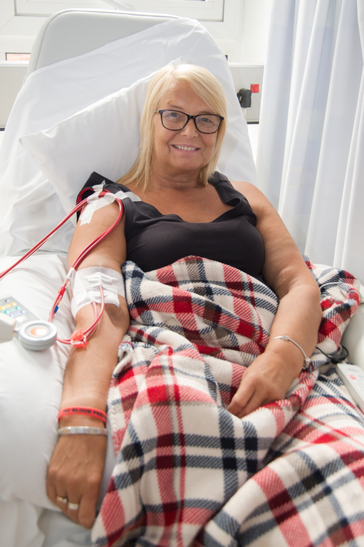 Photograph of a person in bed with a dialysis line in