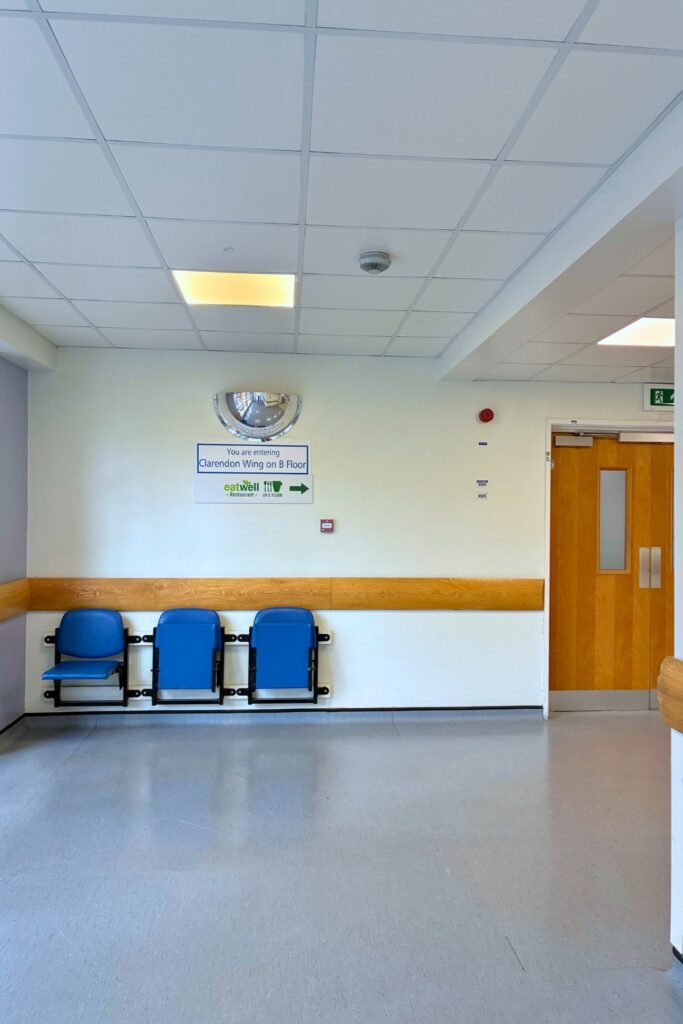 End of link bridge with 3 blue chairs and sign for Clarendon Wing B Floor