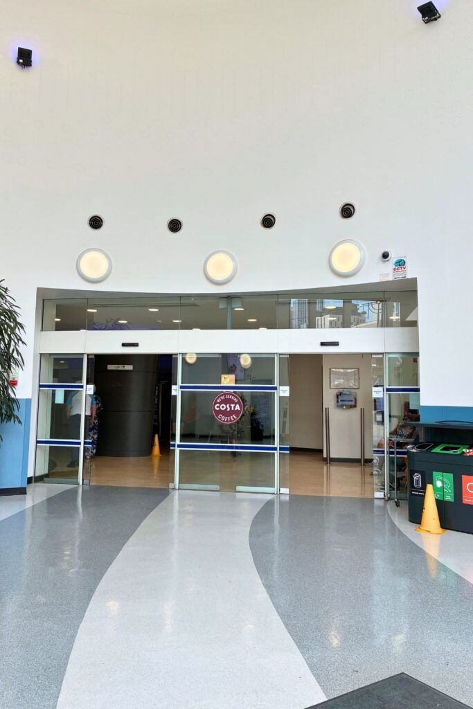 Entrance rotunda with glass automatic doors and a sign for Costa coffee