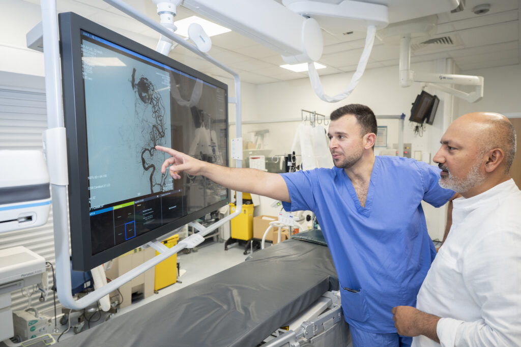 Two men in an operating theatre reviewing a scan