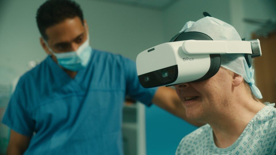 An image of a clinician with a patient who is using a VR headset as part of their treatment.