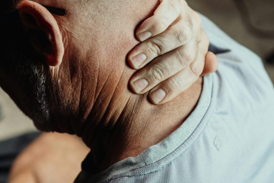 An image of an older male patient holding their neck, representing neck and shoulder pain, one of the key symptoms of polymyalgia rheumatica (PMR)
