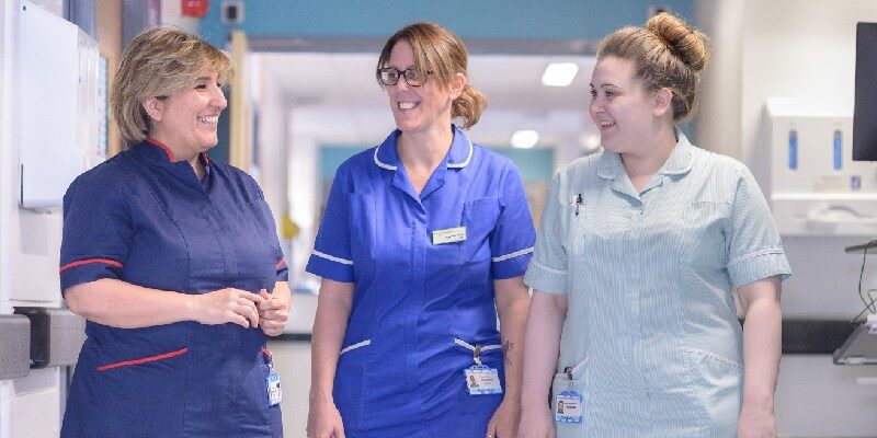 Three female clinicians talking, smiling