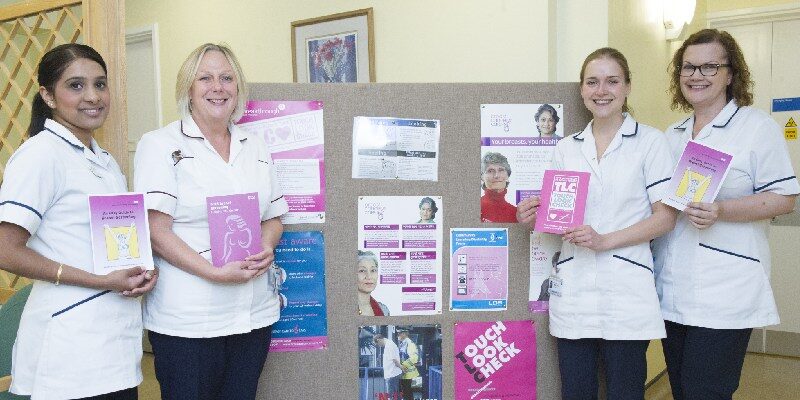 Breast services team infront of a promotional board
