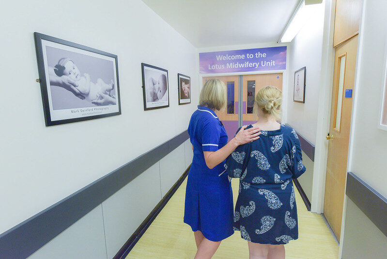 Midwife on corridor directing patient to lotus midwifery led unit.